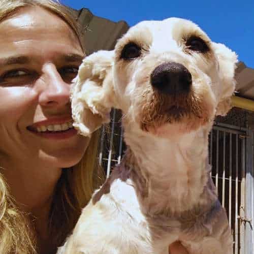 Cuidadora sonriendo mientras sostiene a un perro pequeño en la Residencia Canina Tatinejos en Santander.