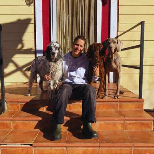 Cuidadora de la Residencia Los Amigos de Erik en Guadalajara acompañada de tres perros en la entrada principal.