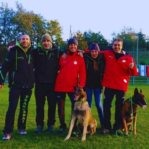 Equipo de la Residencia Canina Txakur Bai en Bilbao posando en un campo verde junto a dos perros, reflejando profesionalismo y dedicación.