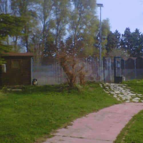 Instalaciones exteriores de la Residencia Canina Fuentes Blancas en Burgos, con caminos pavimentados, áreas verdes y una caseta en un entorno natural.