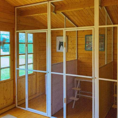 Vista del interior de una jaula de madera con ventanas y paredes de malla en la Residencia Canina Parayas, Santander.