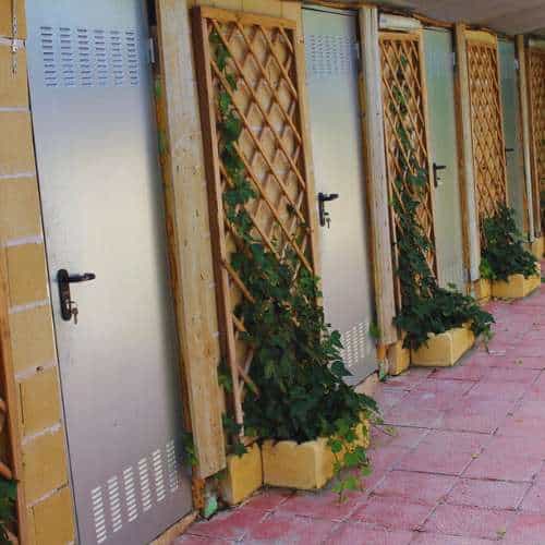 Puertas individuales de jaulas en la residencia canina Herocan en Toledo, decoradas con plantas trepadoras.
