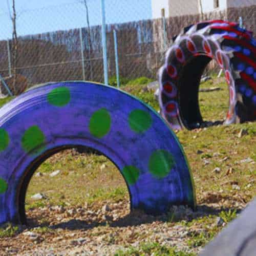 Neumáticos pintados con colores vivos y puntos decorativos utilizados como elementos de juego en la residencia canina Territorio Canino en Toledo.