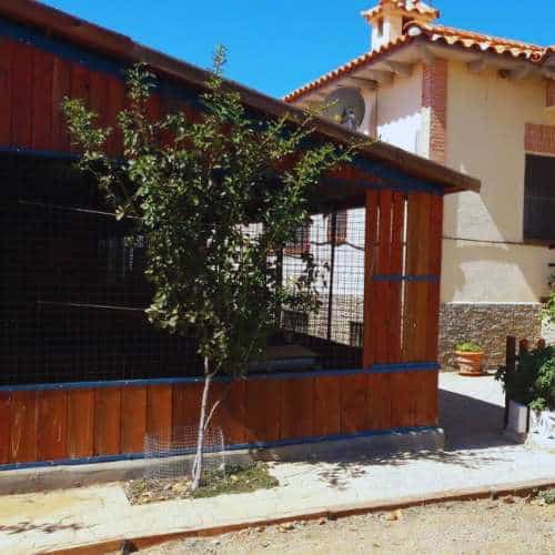 Zona exterior de la Residencia Rivendel en Guadalajara, con jaulas de madera y un entorno acogedor para las mascotas.