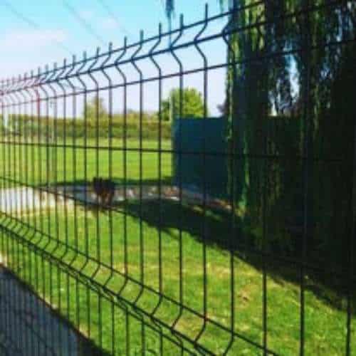 Zona verde vallada en la Residencia Canina Bureba en Burgos, con un perro visible al fondo y rodeada de naturaleza.