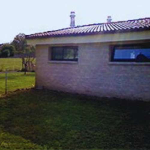 Vista lateral del edificio principal de la Guardería Canina Los Ferreros en Oviedo, rodeado de áreas verdes.
