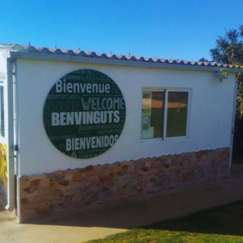 Fachada de la recepción de la Residencia Can Planet, Girona, con un cartel de bienvenida en varios idiomas.